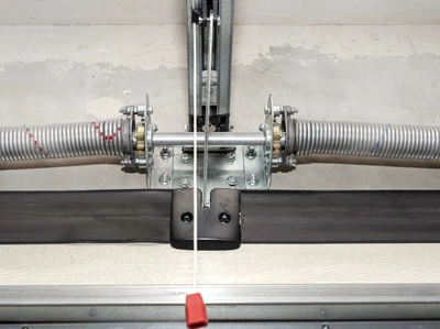 Professional garage door technician performing precise balance and force adjustment testing with specialized equipment, showing expert calibration of spring tension and opener force settings to ensure safe, reliable garage door operation and prevent premature wear for Louisville homeowners