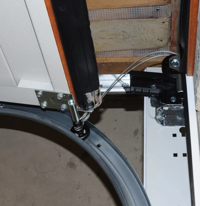 Professional garage door technician replacing damaged lift cables showing frayed cable repair work near garage door drum and pulley system with proper safety equipment for reliable door operation in Louisville homes