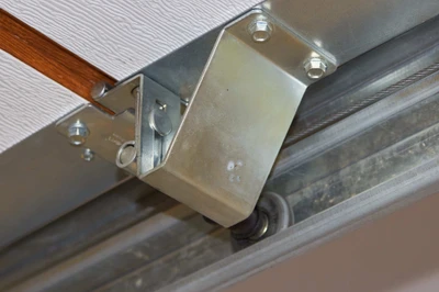 Professional garage door technician installing new nylon rollers and hinges showing expert hardware replacement service with precision tools to reduce noise, improve smooth operation, and extend garage door system lifespan for Louisville homeowners